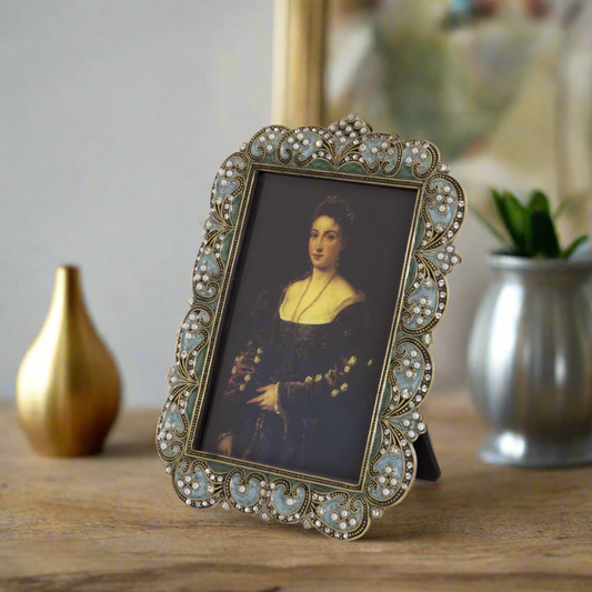 A vintage style swirl picture frame with metal and glass, decorated with pearls and jewels, and a felt back.