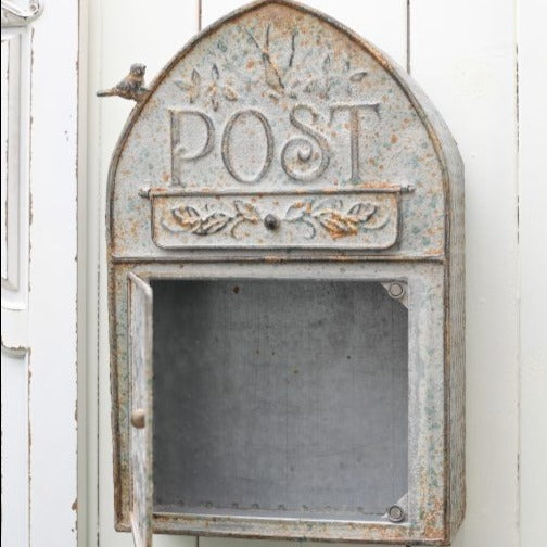 Rustic Metal Post Box, with a small bird perched on the side,. The door to collect the post is open and the post box is hanging on a wall
