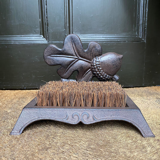 boot brush on a rush matting flooring with a brown door in the background 