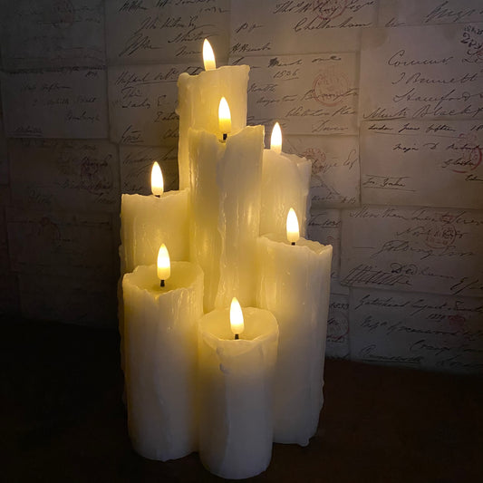 7 piece melted edge candle stack on a wooden mantle with a wallpapered wall in background