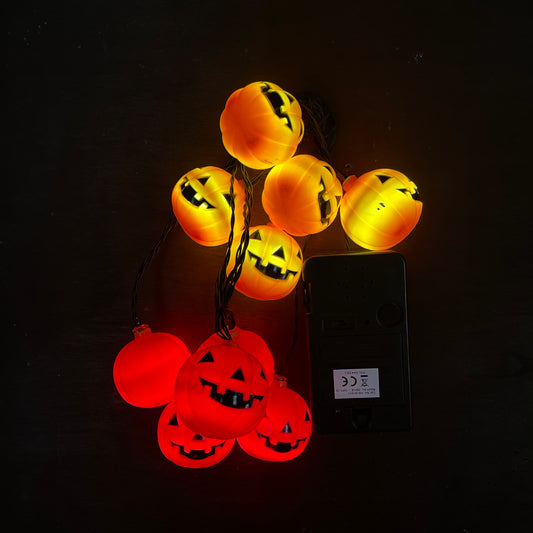 Orange LED pumpkin lights clumped together on a plain backgroud next to the battery box to show of the lights clearer