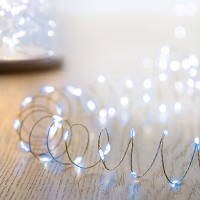 mirco led pin wire lights lay out on a wooden surface in a coil shape to show off the lights