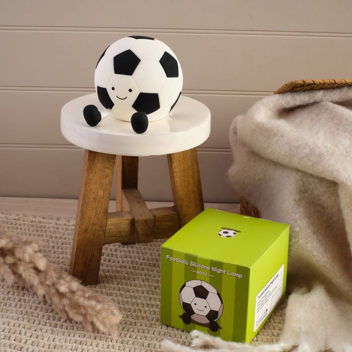 Soccer ball-shaped night light on a small stool next to its packaging box.