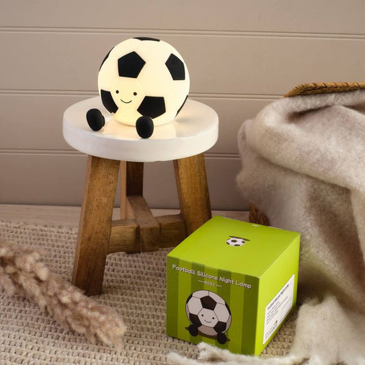 Soccer ball-shaped night light on a small stool next to its packaging box.