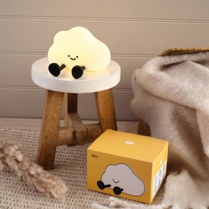 Cute cloud-shaped night light on a small stool next to its packaging box.