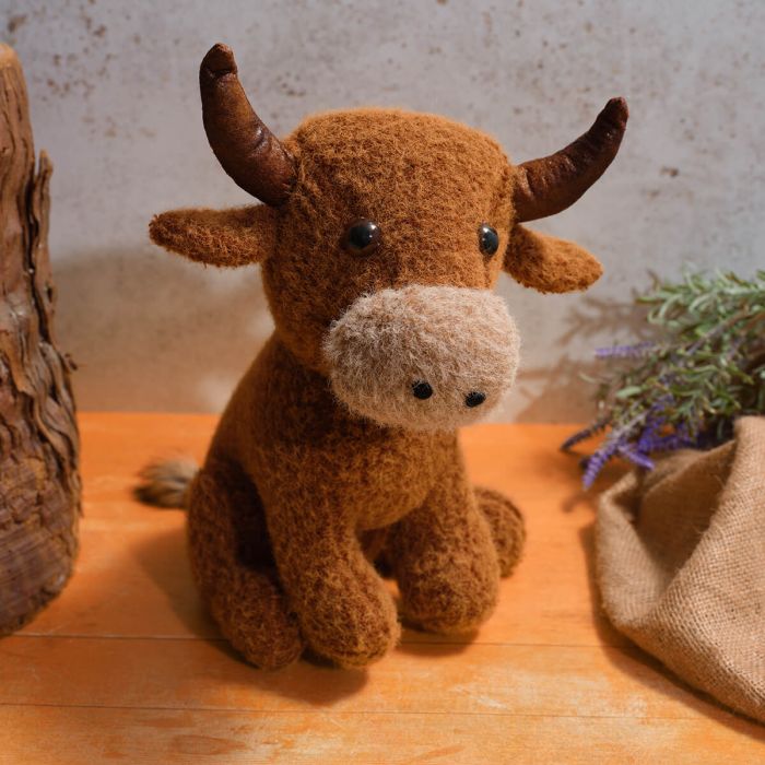 Brown stuffed highland cow with horns on a wooden surface