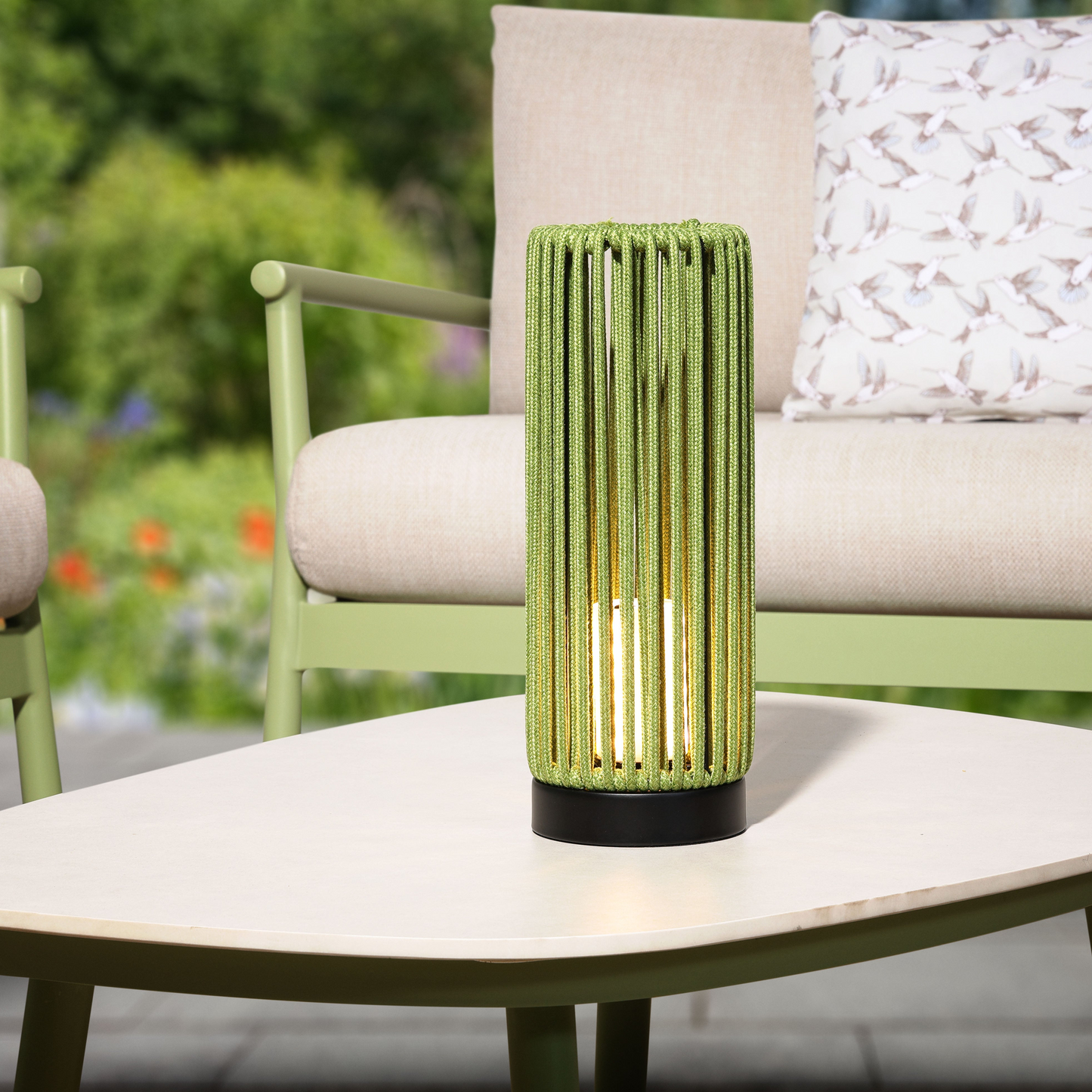 Green outdoor lamp on a table with a blurred garden background