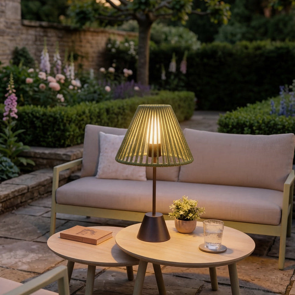 Outdoor patio setting with seating area, table, and lamp in a garden.
