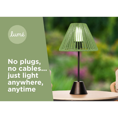 Green lamp on a table with a blurred outdoor background and 'lumé' branding.