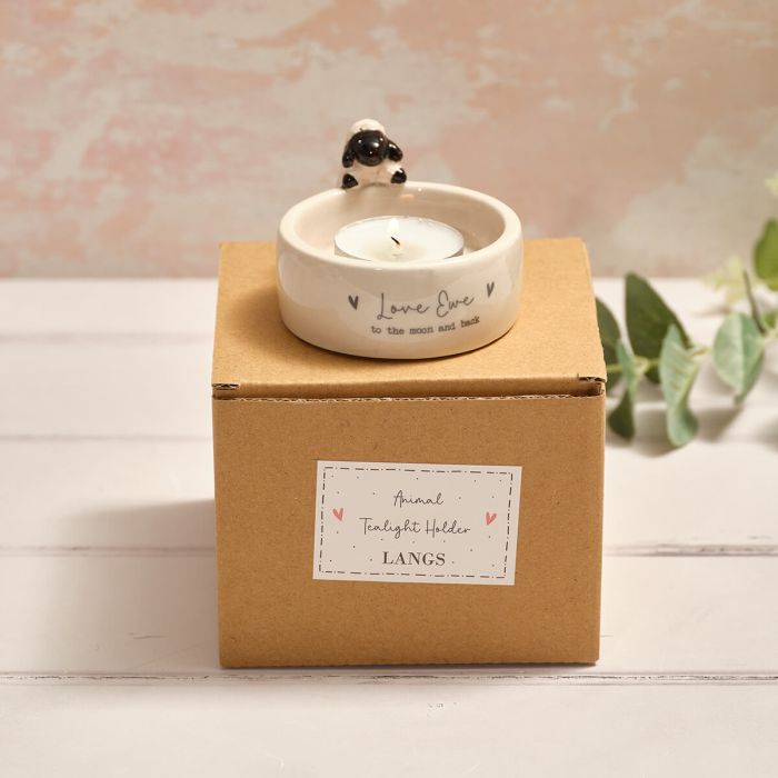 Tealight holder with a small sheep design on a cardboard box labeled 'LANGS'.
