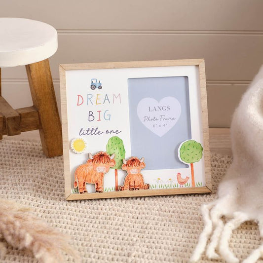Framed children's photo frame with 'Dream Big little one' text and cartoon highland cows on a textured surface.