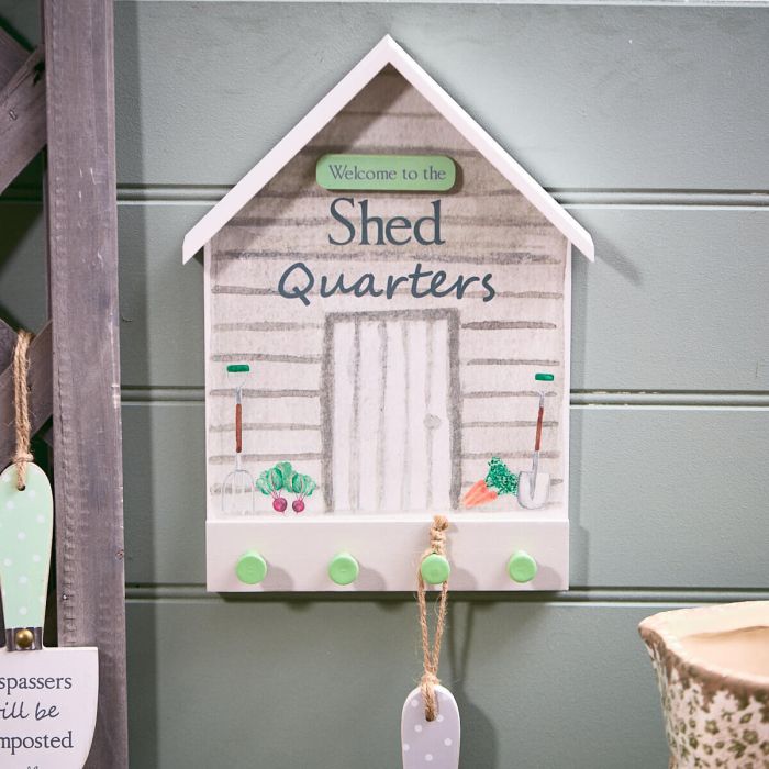 Decorative sign with 'Welcome to the Shed Quarters' text on a gray wall.