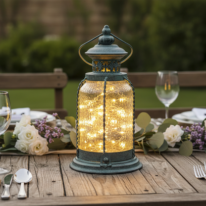 Decorative lantern with string lights on a table set for dinner outdoors.
