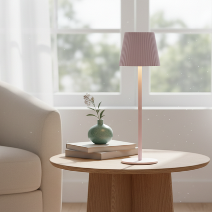 Round wooden table with a lamp, books, and a vase in a bright living room.