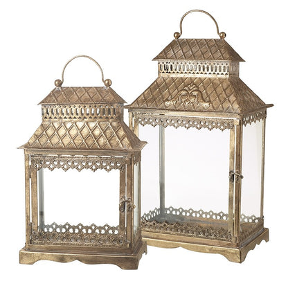 A set of two golden colored metal lanterns with glass panels, featuring intricate designs and hanging loops.