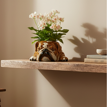 Decorative pot shaped like a bulldog head with flowers on a wooden shelf.